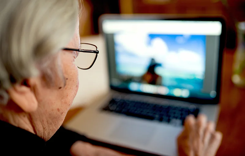 Ältere Frau mit Brille am Laptop